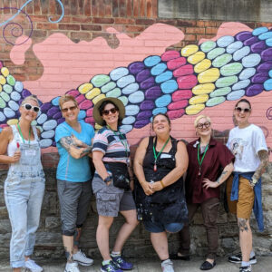 mural artists standing in front of Friendship Bracelet mural at Gillian’s Place 2023